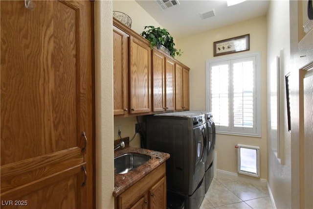 laundry room with visible vents, a sink, washing machine and dryer, cabinet space, and light tile patterned floors