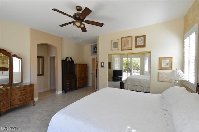 bedroom featuring baseboards, multiple windows, arched walkways, and light tile patterned flooring