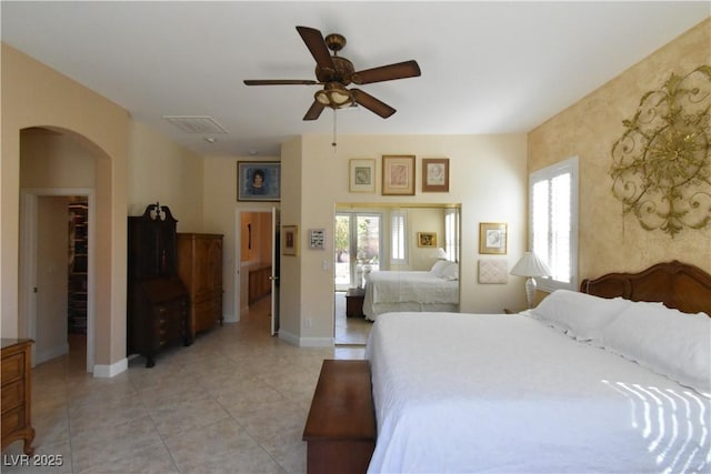 bedroom with arched walkways, light tile patterned floors, multiple windows, and baseboards