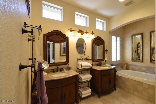 full bath with visible vents, a healthy amount of sunlight, two vanities, and a sink