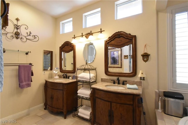 bathroom with two vanities, baseboards, and a sink