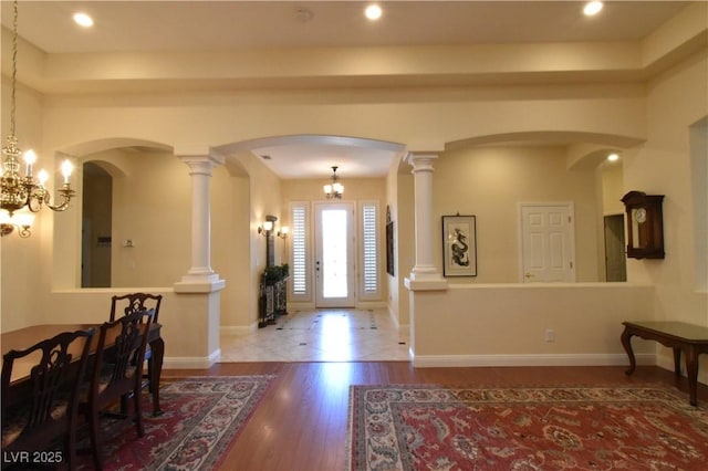 entryway featuring wood finished floors, baseboards, a chandelier, and arched walkways