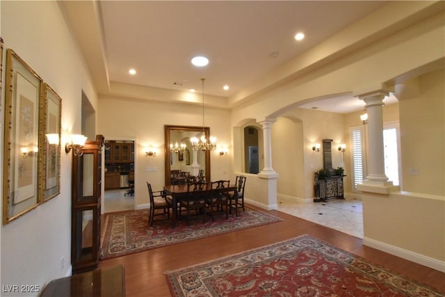 dining space featuring decorative columns, wood finished floors, arched walkways, and baseboards