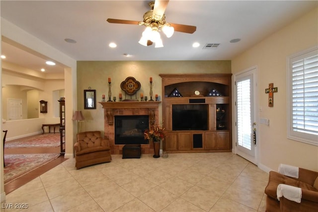 living area featuring light tile patterned floors, a ceiling fan, visible vents, a fireplace, and recessed lighting