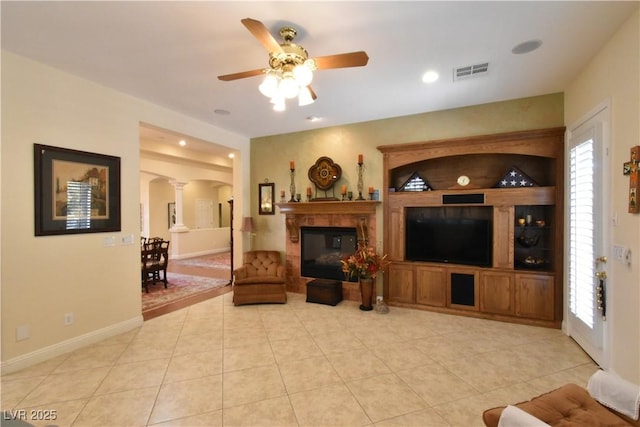 living room featuring baseboards, visible vents, decorative columns, light tile patterned flooring, and ceiling fan