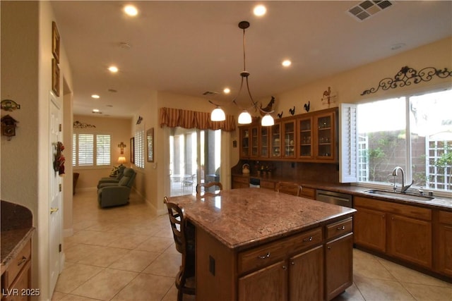 kitchen with light tile patterned flooring, a kitchen island, visible vents, and a sink