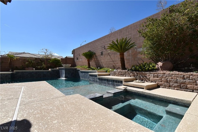 view of swimming pool with a fenced backyard and a pool with connected hot tub