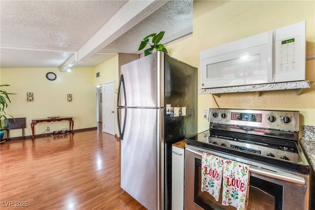 kitchen with baseboards, a textured ceiling, appliances with stainless steel finishes, and light wood finished floors