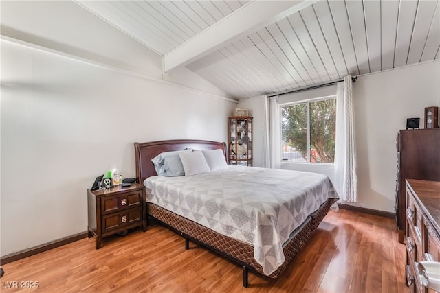 bedroom with wooden ceiling, vaulted ceiling with beams, light wood-style floors, and baseboards