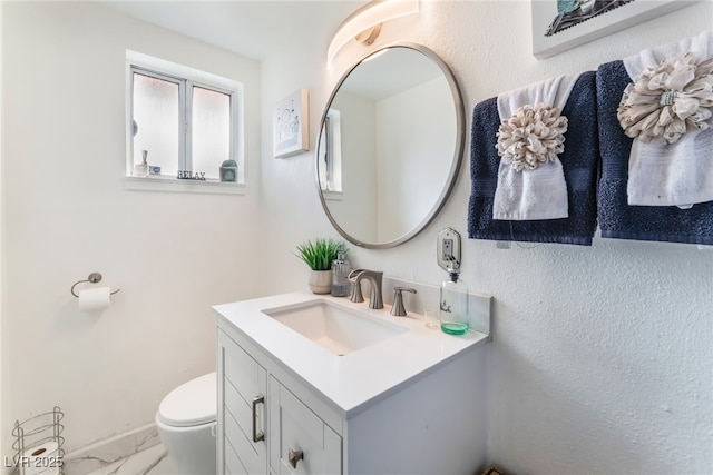 bathroom with vanity, toilet, and marble finish floor