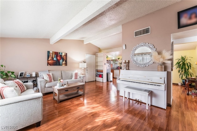 living area with visible vents, wood finished floors, and vaulted ceiling with beams