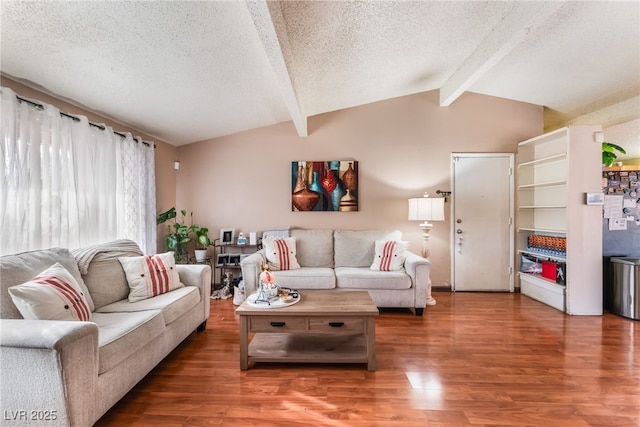 living area featuring lofted ceiling with beams, wood finished floors, and a textured ceiling