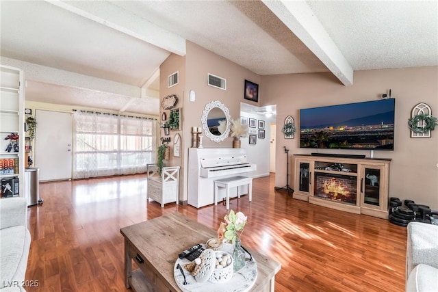 living area with lofted ceiling with beams, visible vents, and a textured ceiling