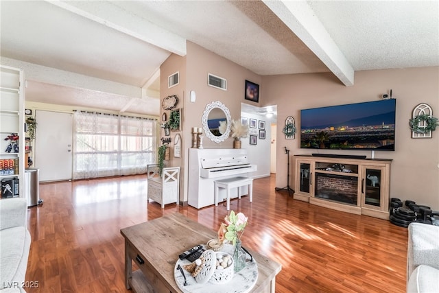 living room with visible vents, a textured ceiling, and vaulted ceiling with beams