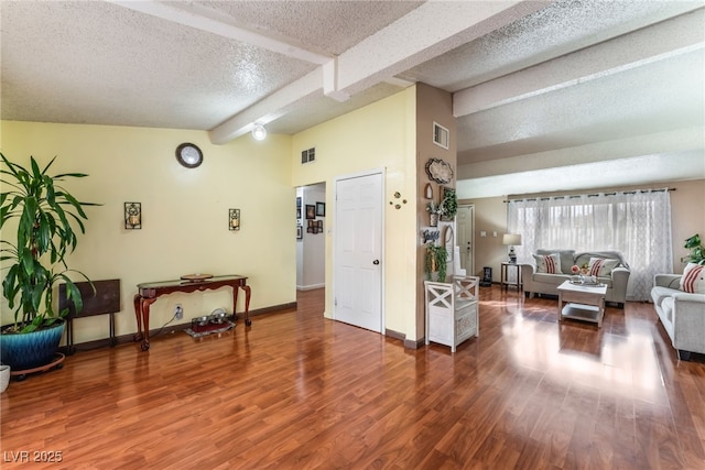 living room featuring baseboards, wood finished floors, visible vents, and a textured ceiling