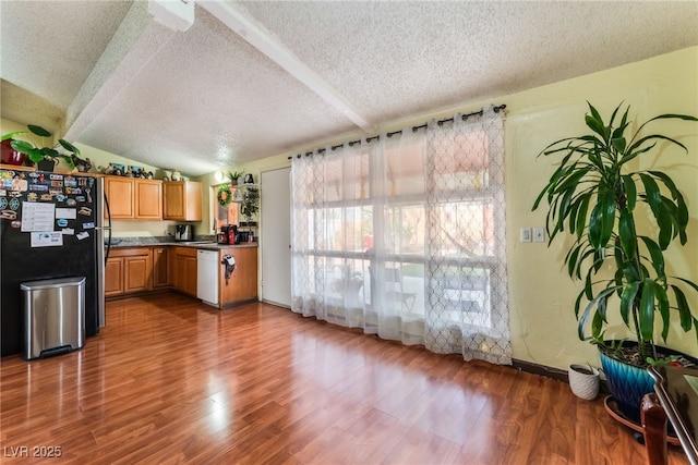 kitchen with wood finished floors, lofted ceiling with beams, freestanding refrigerator, a textured ceiling, and dishwasher