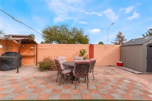 view of patio / terrace featuring outdoor dining area, fence, an outbuilding, and a shed