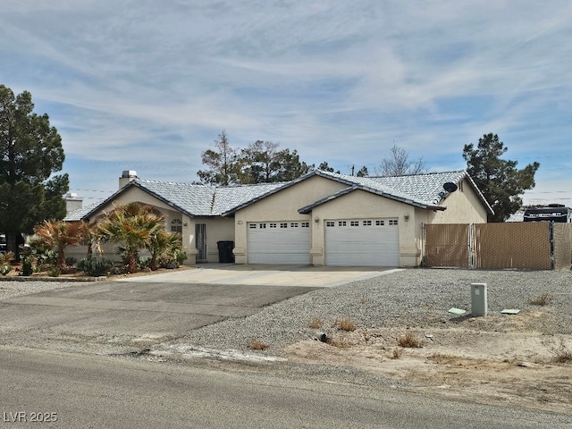 ranch-style home with fence, driveway, an attached garage, stucco siding, and a tile roof