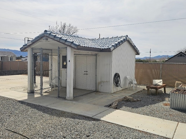 view of outbuilding featuring a mountain view, fence, an outdoor structure, and an exterior structure