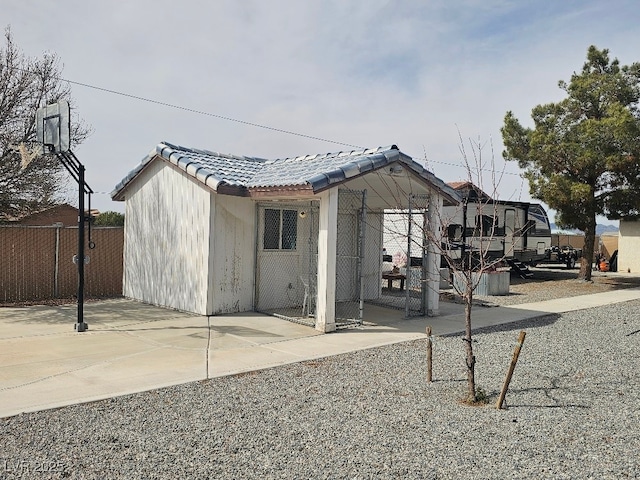 view of home's exterior with a patio area, a tiled roof, and fence