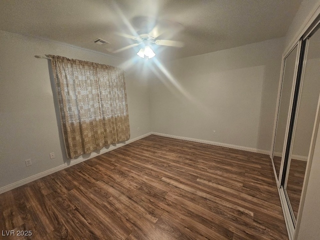 unfurnished bedroom with a closet, baseboards, and dark wood finished floors