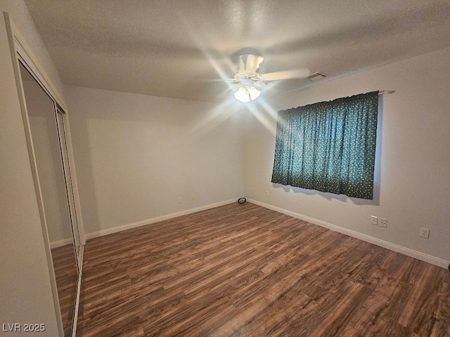 unfurnished bedroom with a closet, baseboards, dark wood finished floors, and visible vents