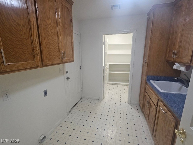 laundry room featuring electric dryer hookup, light floors, visible vents, cabinet space, and a sink