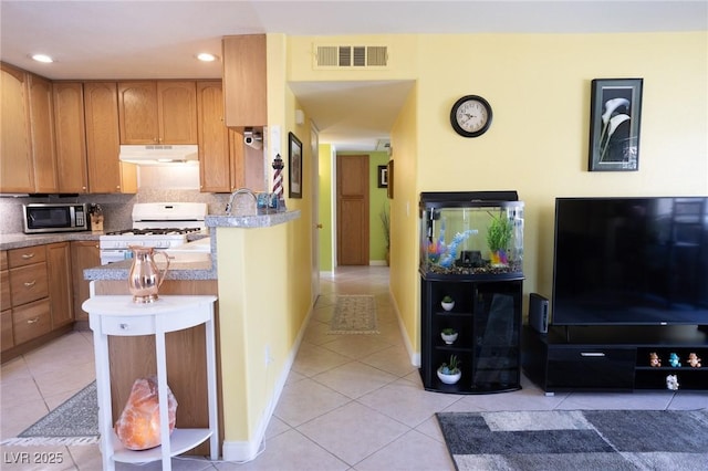 5206 Mandalay Springs Dr Unit 204, Las Vegas, NV 89120 - kitchen with visible vents, light tile patterned floors, gas range gas stove, under cabinet range hood, and stainless steel microwave