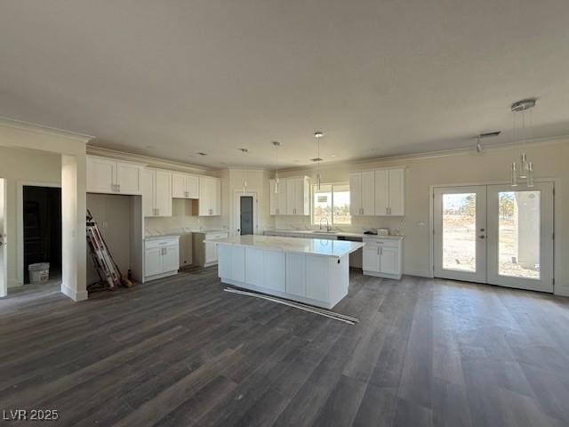 kitchen with crown molding, white cabinets, dark wood-type flooring, and a center island