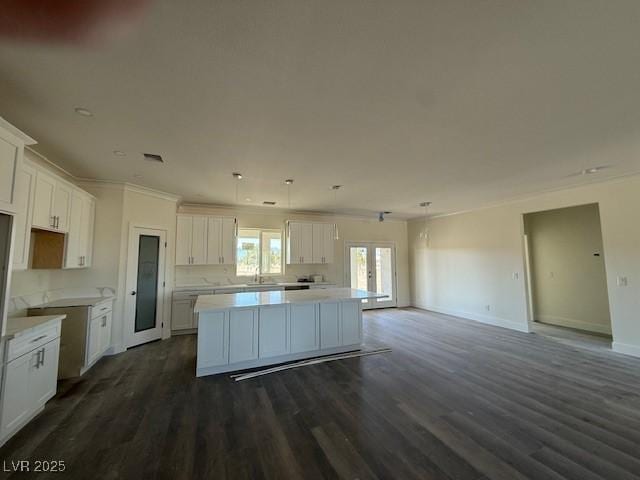 kitchen featuring a center island, dark wood-type flooring, baseboards, light countertops, and white cabinetry