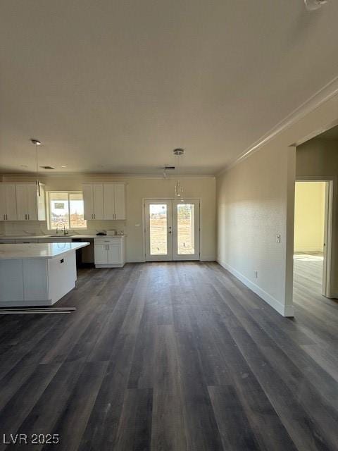 unfurnished living room with crown molding, french doors, dark wood-style floors, and a wealth of natural light