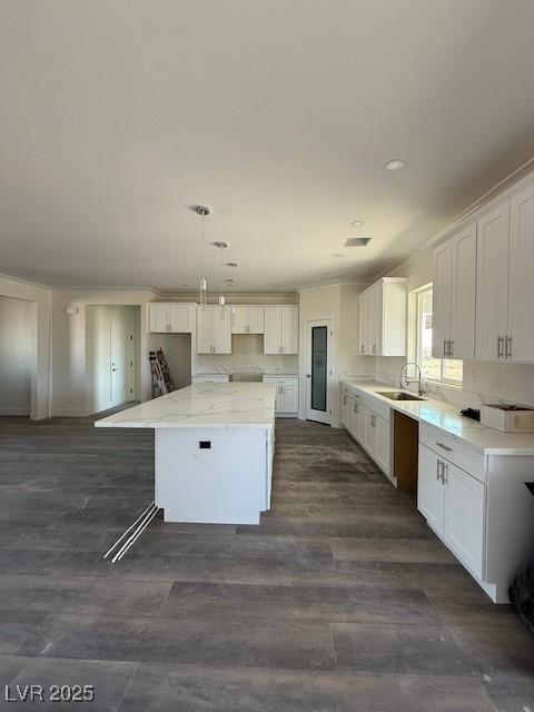 kitchen featuring a sink, dark wood finished floors, a center island, and white cabinetry