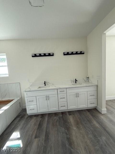 bathroom featuring double vanity, wood finished floors, baseboards, and a sink
