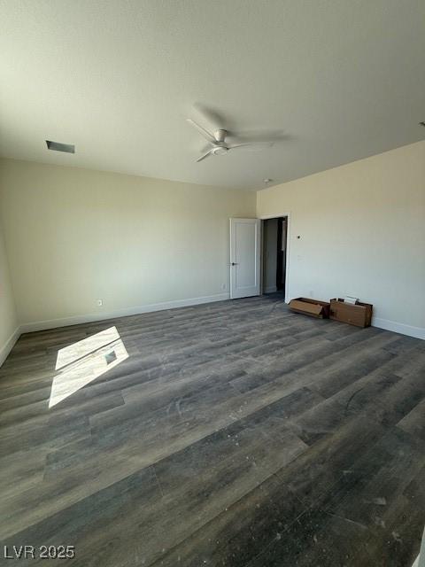 spare room with dark wood finished floors, visible vents, baseboards, and ceiling fan