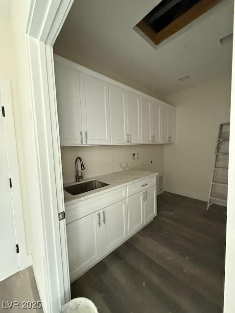 kitchen with dark wood finished floors, light countertops, white cabinets, and a sink