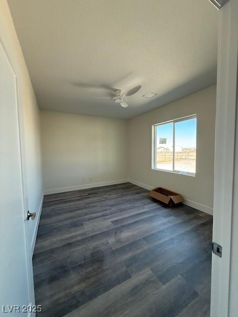 spare room with baseboards, ceiling fan, and dark wood finished floors