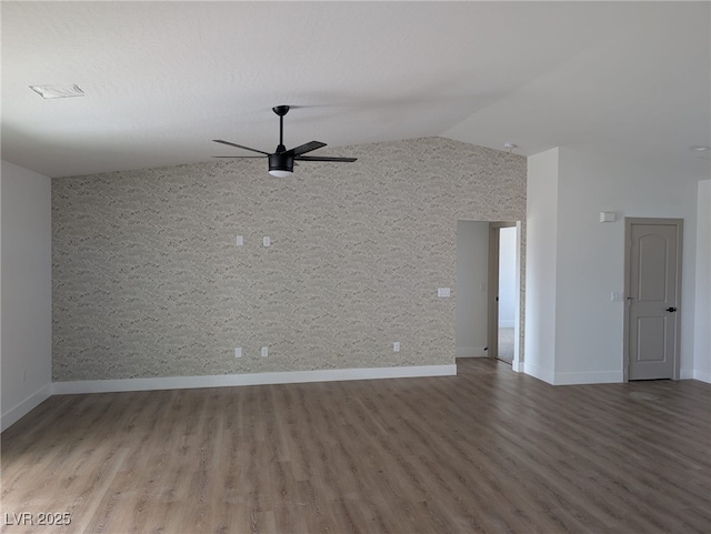 empty room with baseboards, lofted ceiling, wood finished floors, and a ceiling fan