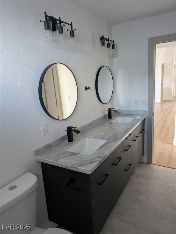 bathroom featuring toilet, a sink, and double vanity