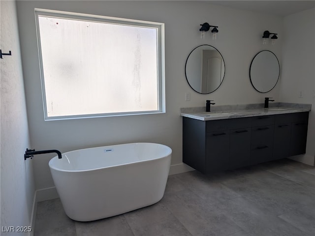full bathroom with a freestanding tub, double vanity, baseboards, and a sink