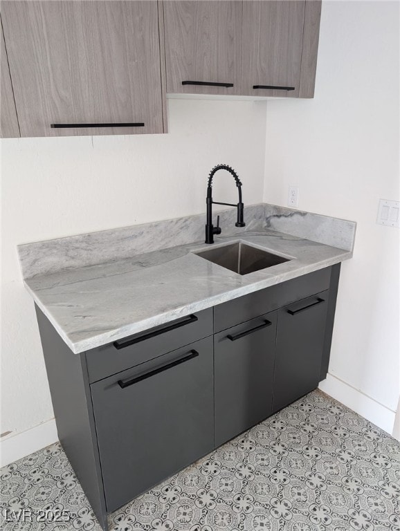 kitchen featuring gray cabinets, a sink, modern cabinets, and baseboards