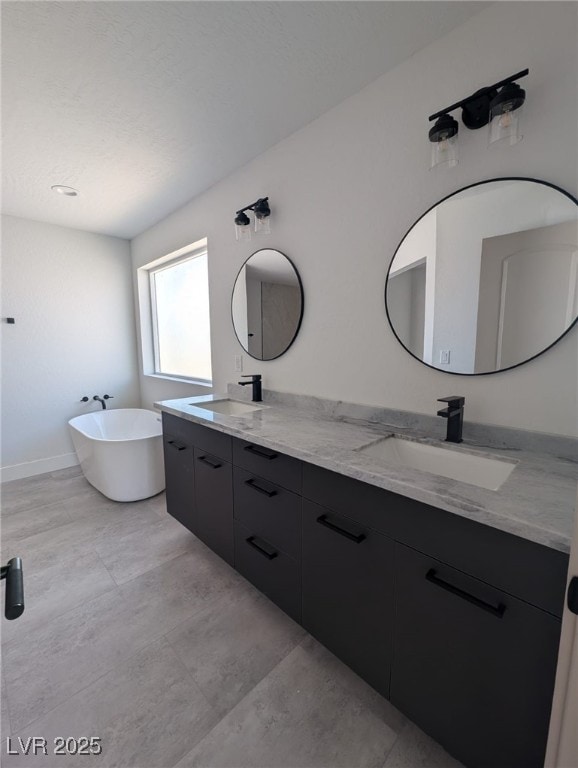 bathroom featuring a soaking tub, double vanity, a sink, and baseboards