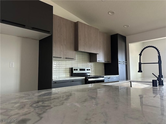 kitchen with decorative backsplash, light stone countertops, a sink, and stainless steel electric range oven