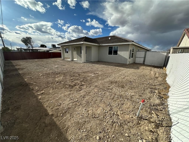 back of property with stucco siding and a fenced backyard