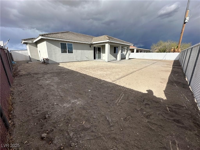 rear view of property with stucco siding and a fenced backyard