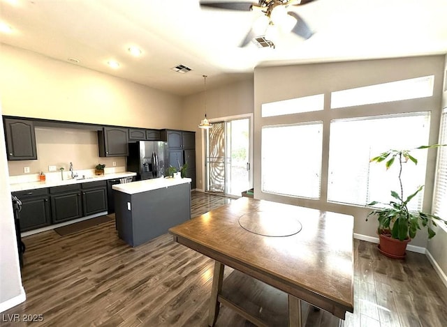 981 Leadville Meadows Dr, Henderson, NV 89052 - kitchen featuring stainless steel fridge with ice dispenser, a center island, light countertops, dark wood finished floors, and a sink
