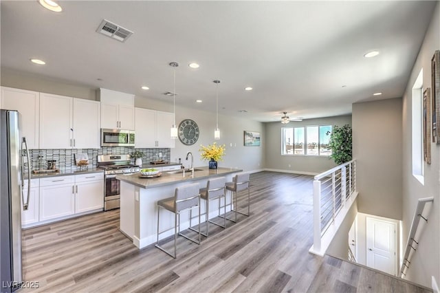 8629 Ensworth St Unit 114, Las Vegas, NV 89123 - kitchen featuring stainless steel appliances, white cabinetry, light wood-type flooring, tasteful backsplash, and recessed lighting