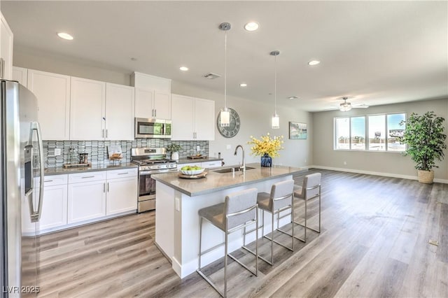 8629 Ensworth St Unit 114, Las Vegas, NV 89123 - kitchen with stainless steel appliances, decorative backsplash, light wood finished floors, white cabinetry, and recessed lighting