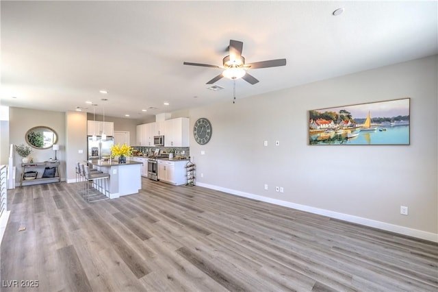 8629 Ensworth St Unit 114, Las Vegas, NV 89123 - kitchen with stainless steel appliances, a breakfast bar, a ceiling fan, white cabinets, and recessed lighting