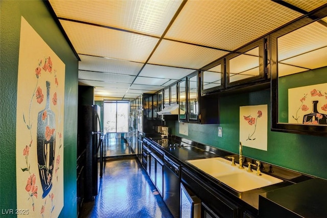 kitchen featuring glass insert cabinets, under cabinet range hood, a drop ceiling, black appliances, and a sink