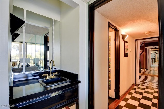 hallway featuring tile patterned floors, a textured ceiling, and a sink